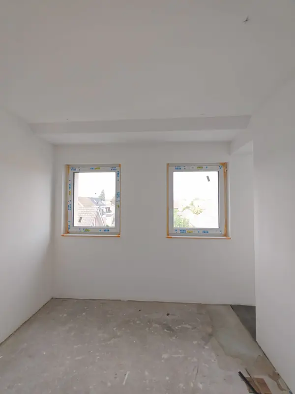 Zimmer mit zwei Fenstern und weißen Wänden