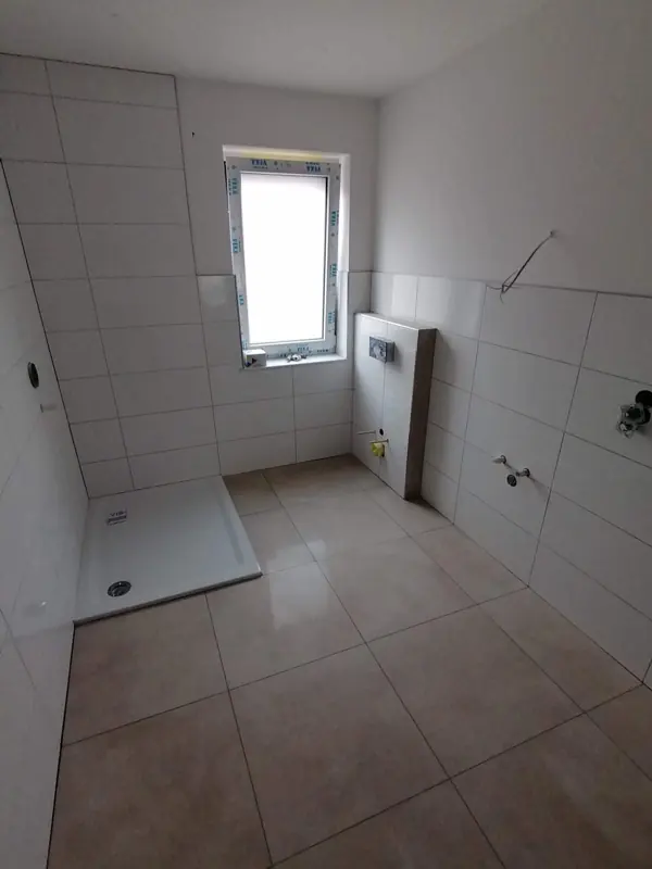 Gefliestes Bad mit Duschwanne und Fenster
