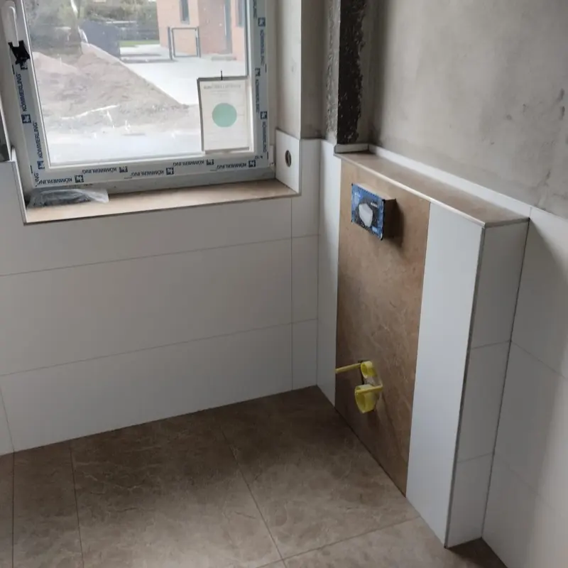 Bad mit weißen Wandfliesen und Vorwandinstallation für das WC
